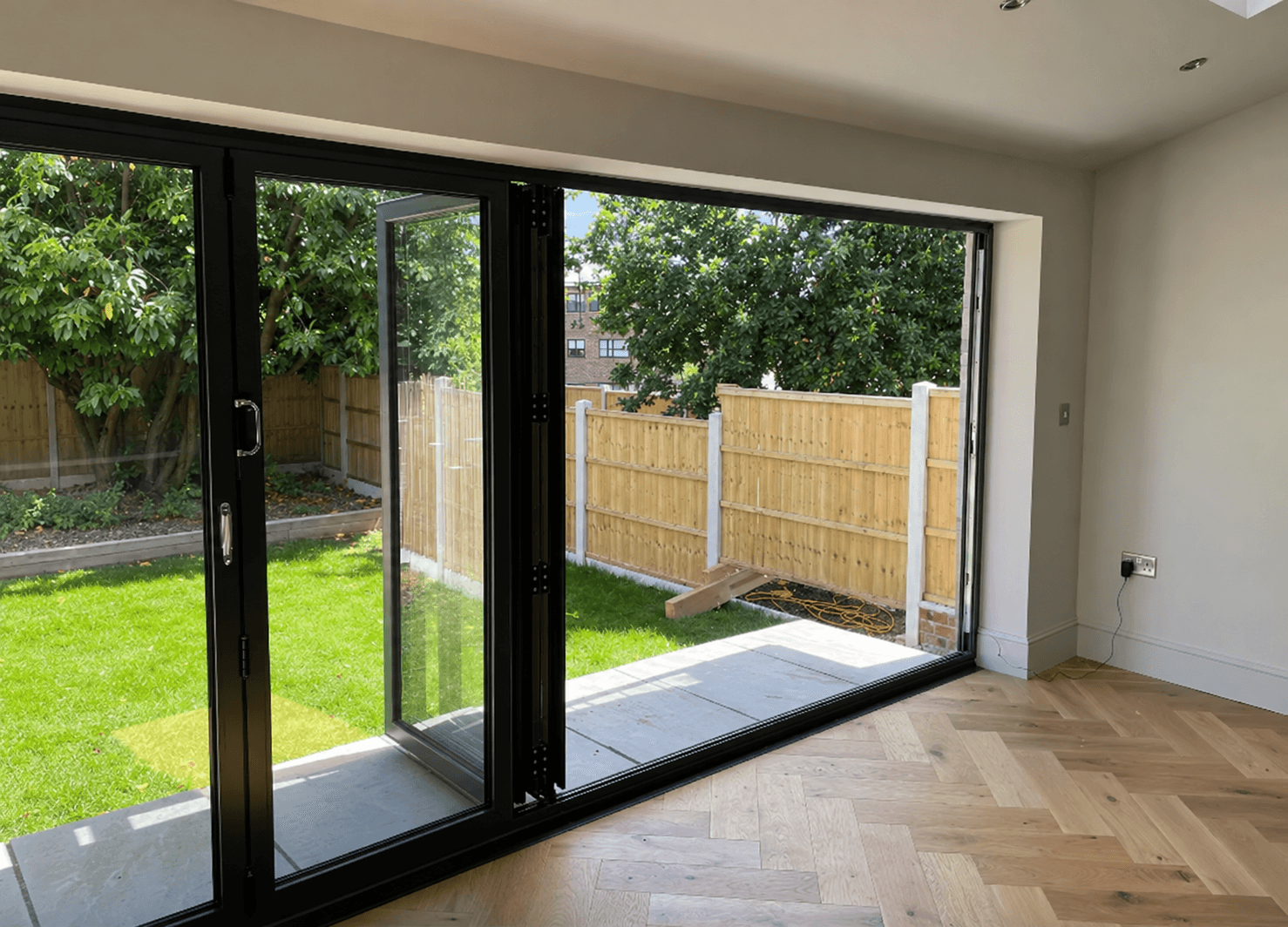 Finished extension interior with herringbone flooring and bifold doors opening onto the garden